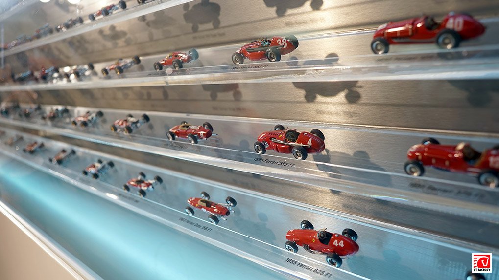 Chronological display of Ferrari racing car models with chassis and race numbers